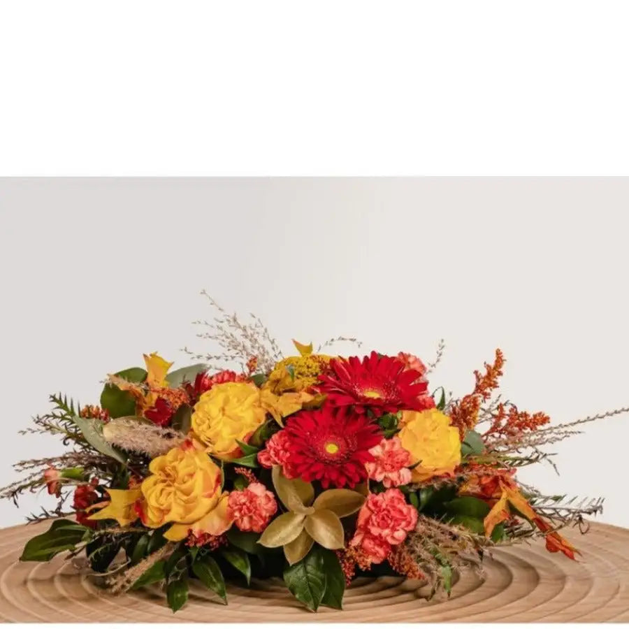 Colorful flower arrangement on a wooden surface with a light gray background