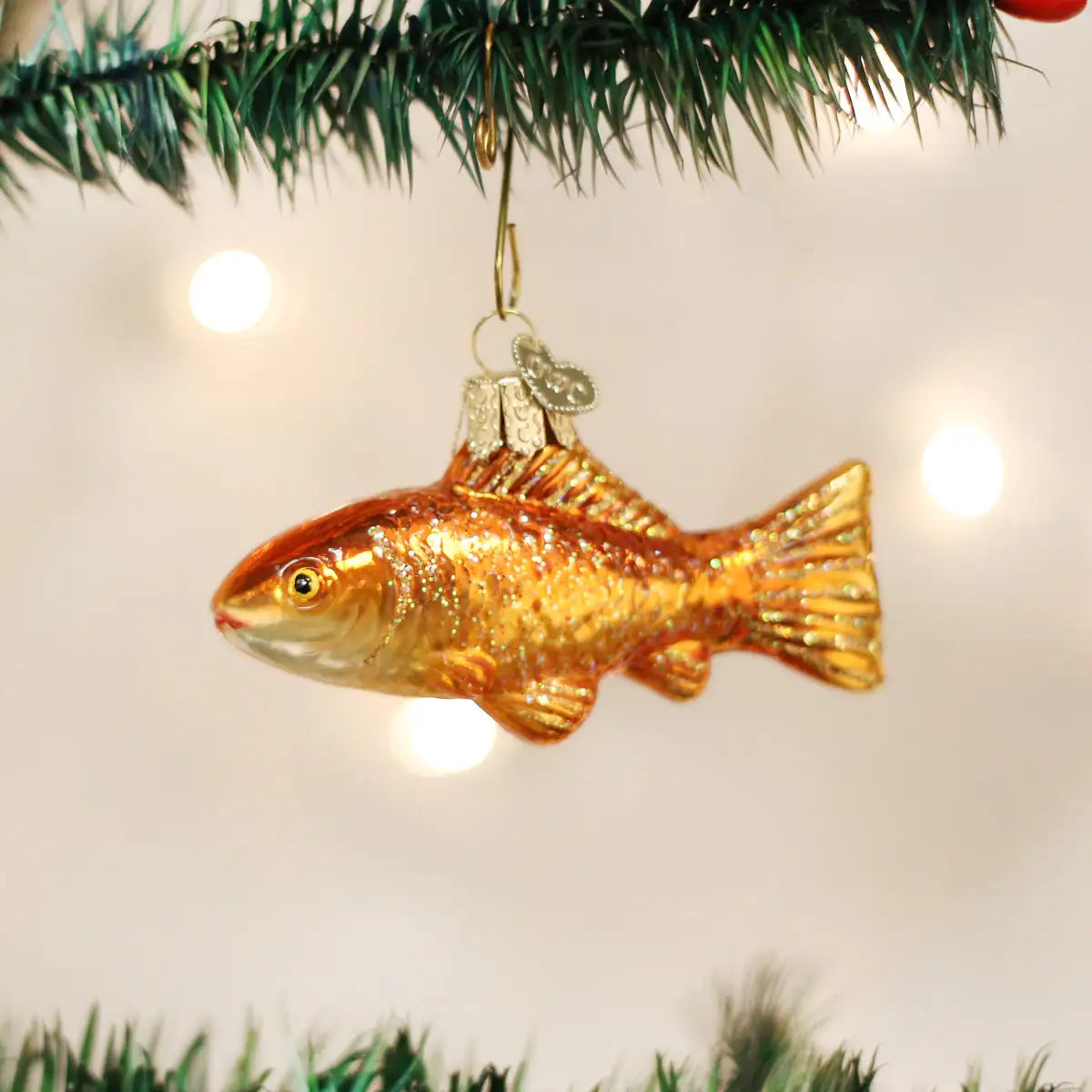 Goldfish ornament hanging on a Christmas tree with lights in the background