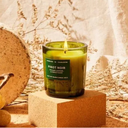 Green candle labeled 'Pinot Noir' on a stone block with a natural background