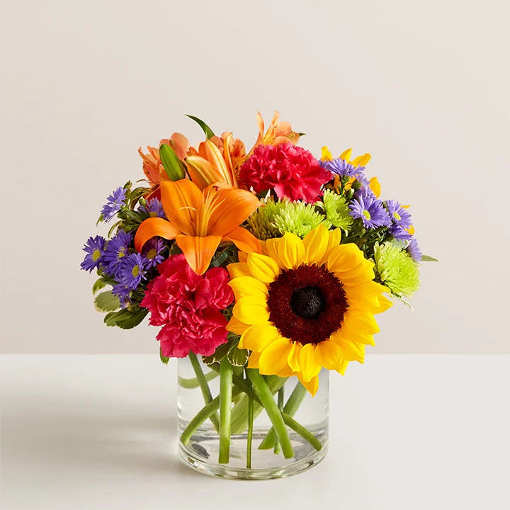 Bouquet of colorful flowers in a clear vase on a light background