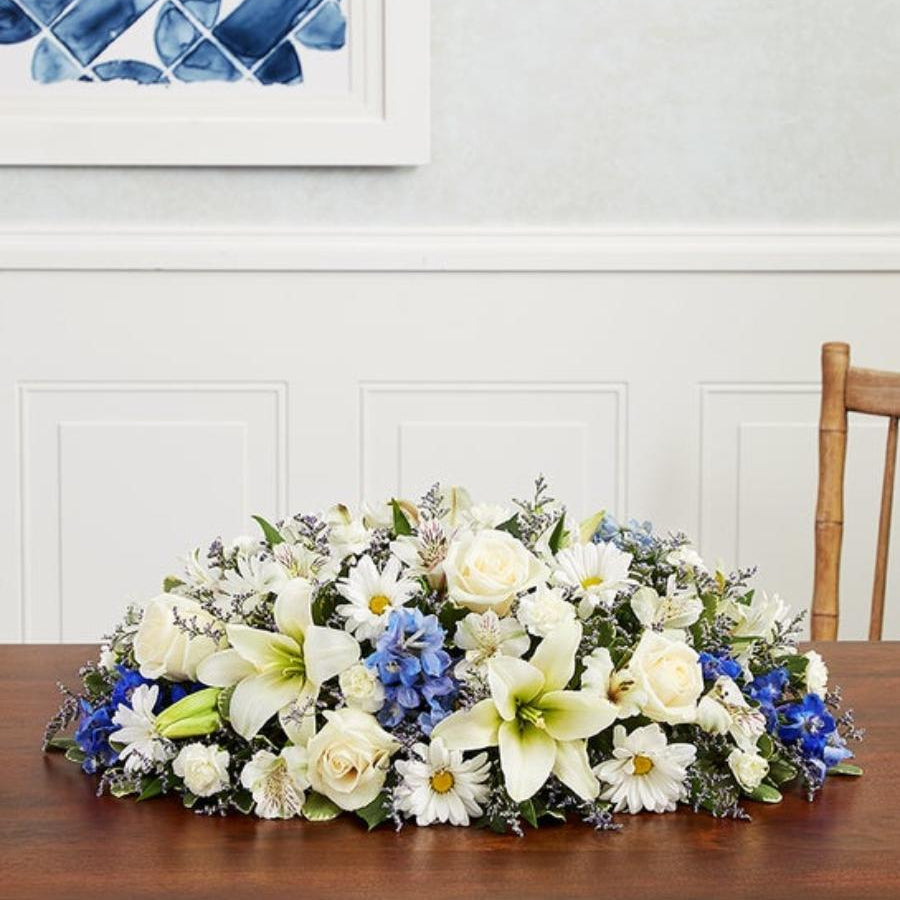 Floral arrangement on a wooden table with a white wall and blue decorative tile in the background