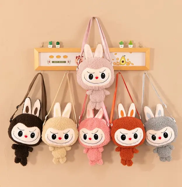 Set of plush bag characters with different colors hanging on a beige wall.