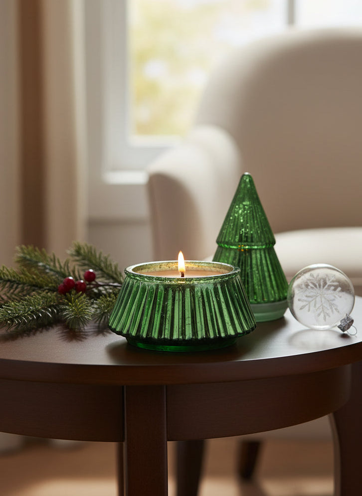 Two green glass candle holders with one lit candle on a white background
