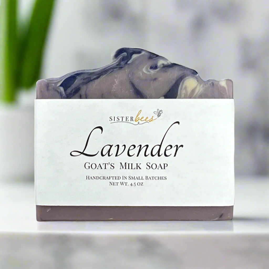 A bar of lavender goat's milk soap with a label that reads 'Sister Bees Lavender Goat's Milk Soap, handcrafted in small batches, net wt. 4 oz.