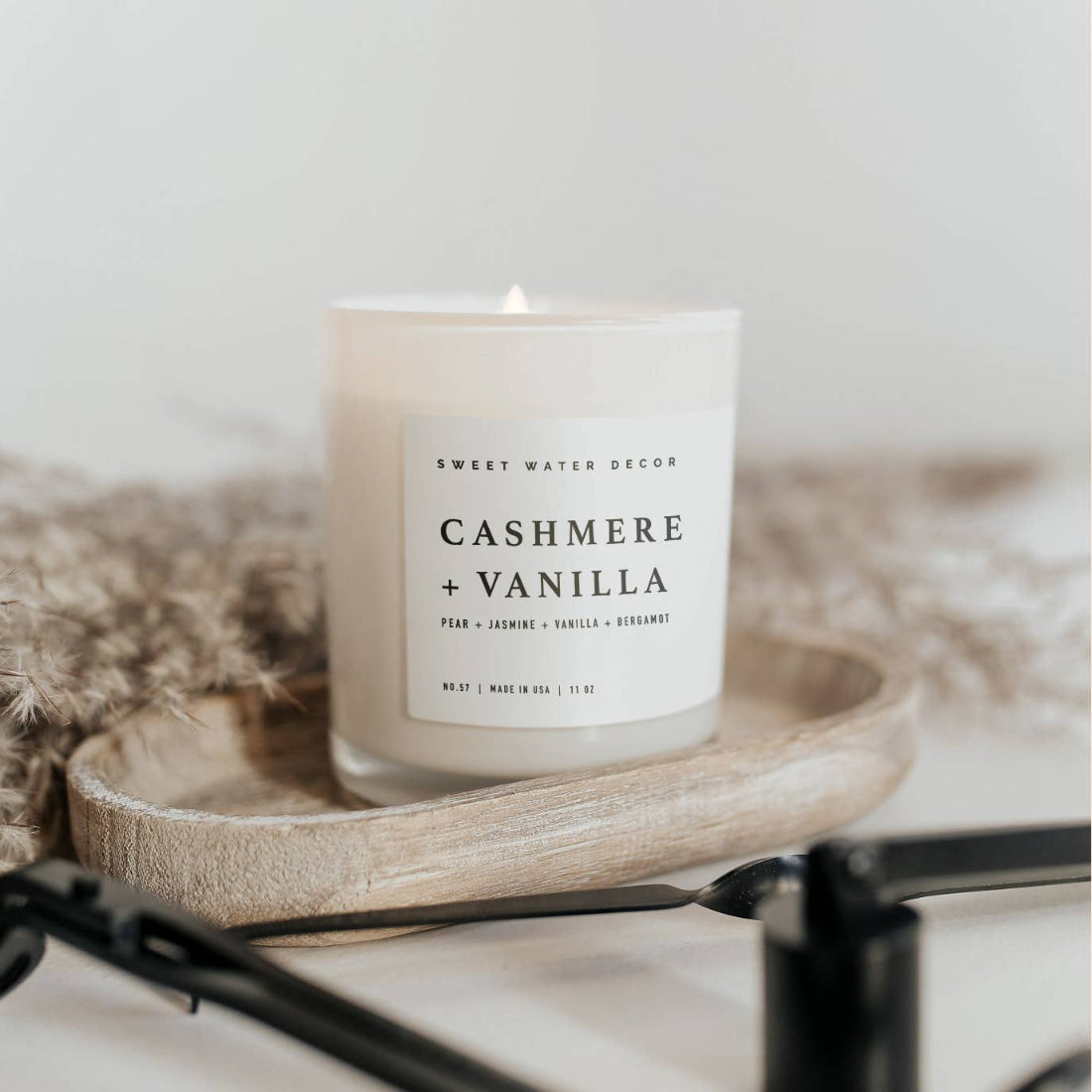 Candle labeled 'Cashmere + Vanilla' on a wooden tray with a neutral background