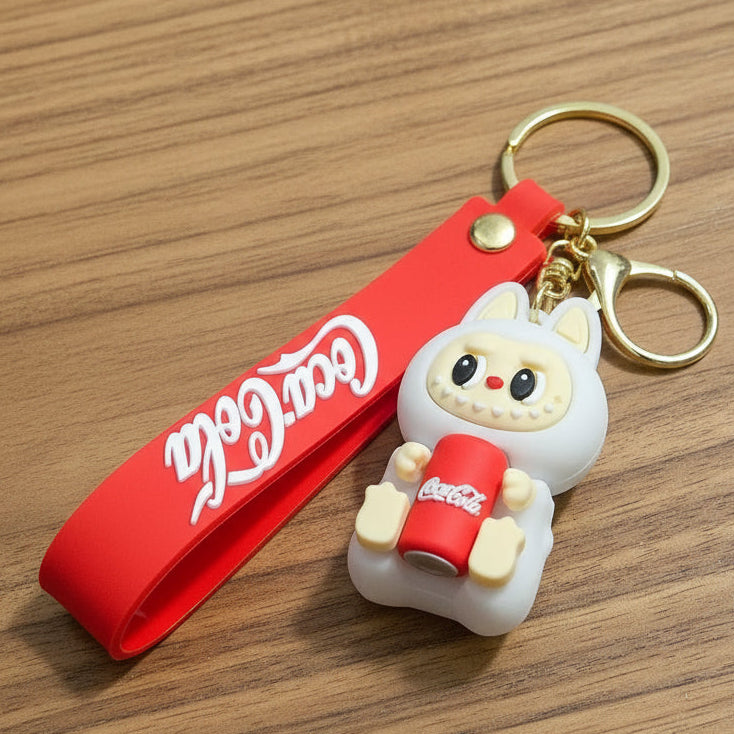 Coca-Cola keychain held in a hand with a blurred cafe background