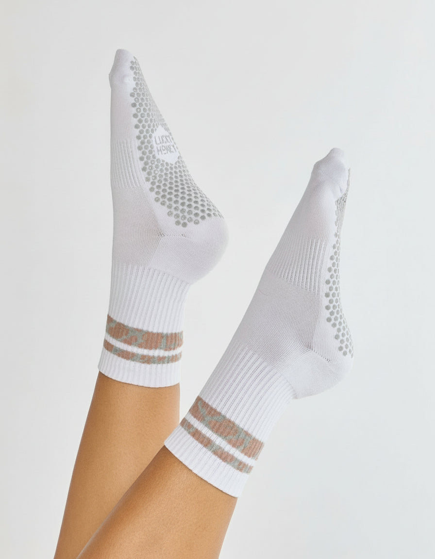 White socks with mesh design and brown stripes on a light gray background