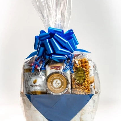 Gift basket with various products including snacks and a large red bow on a gray background