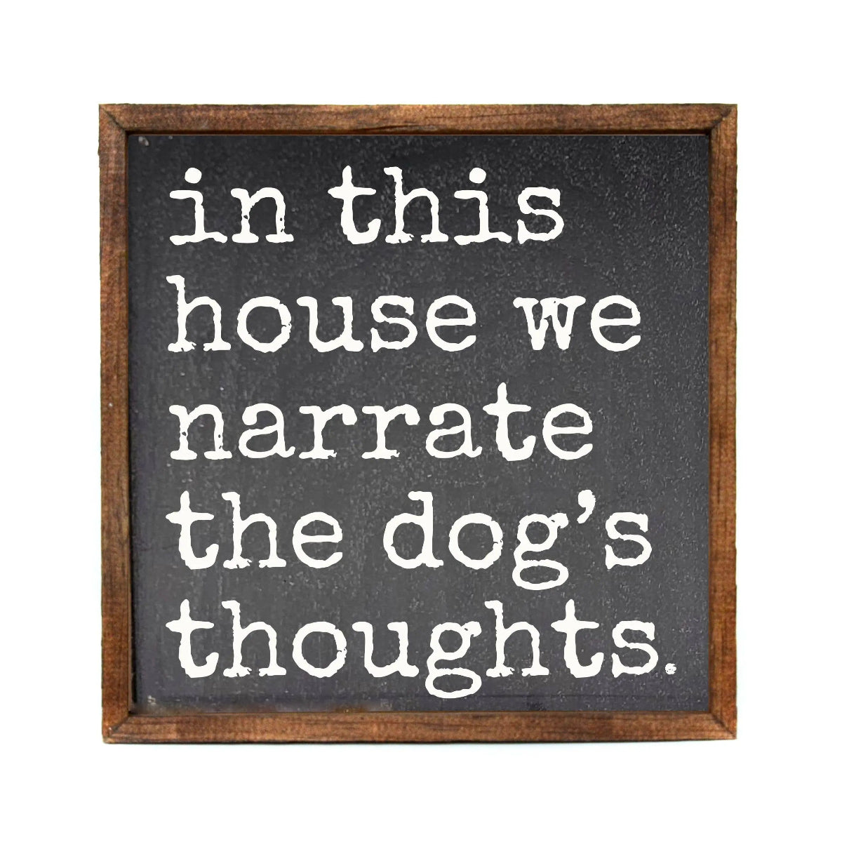 Decorative sign with text 'in this house we narrate the dog's thoughts' on a black background with a wooden frame.