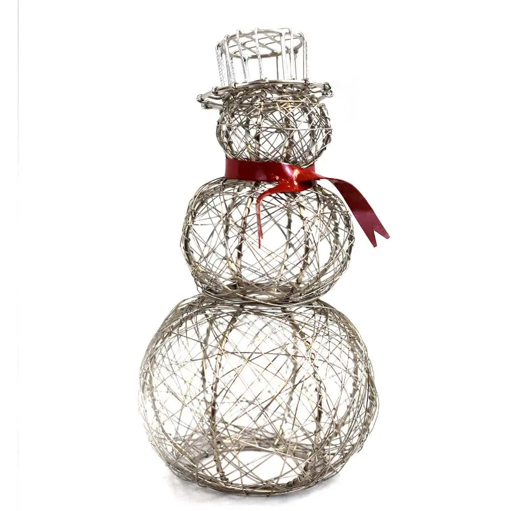 Decorative silver snowman ornament on a Christmas-themed tablecloth with blurred festive background.