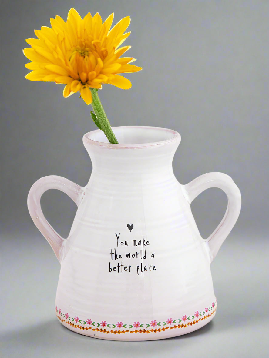 White vase with yellow flower and 'You make the world a better place' text on a light background