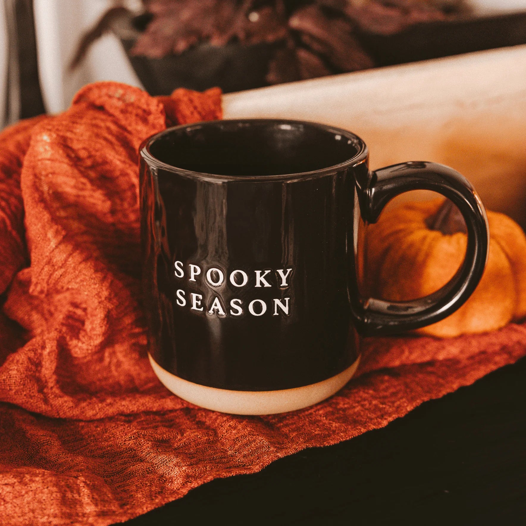 Black mug with 'Spooky Season' text on a red fabric background