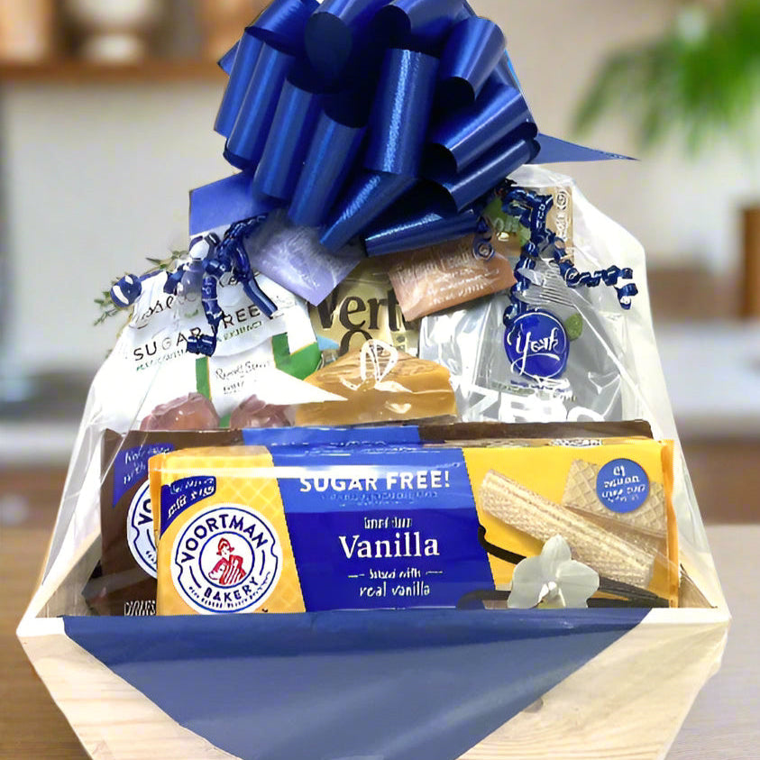 Gift basket with a blue bow containing snacks and treats on a wooden surface.