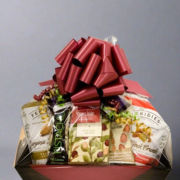 Gift basket with snacks and a large red bow on a gray background