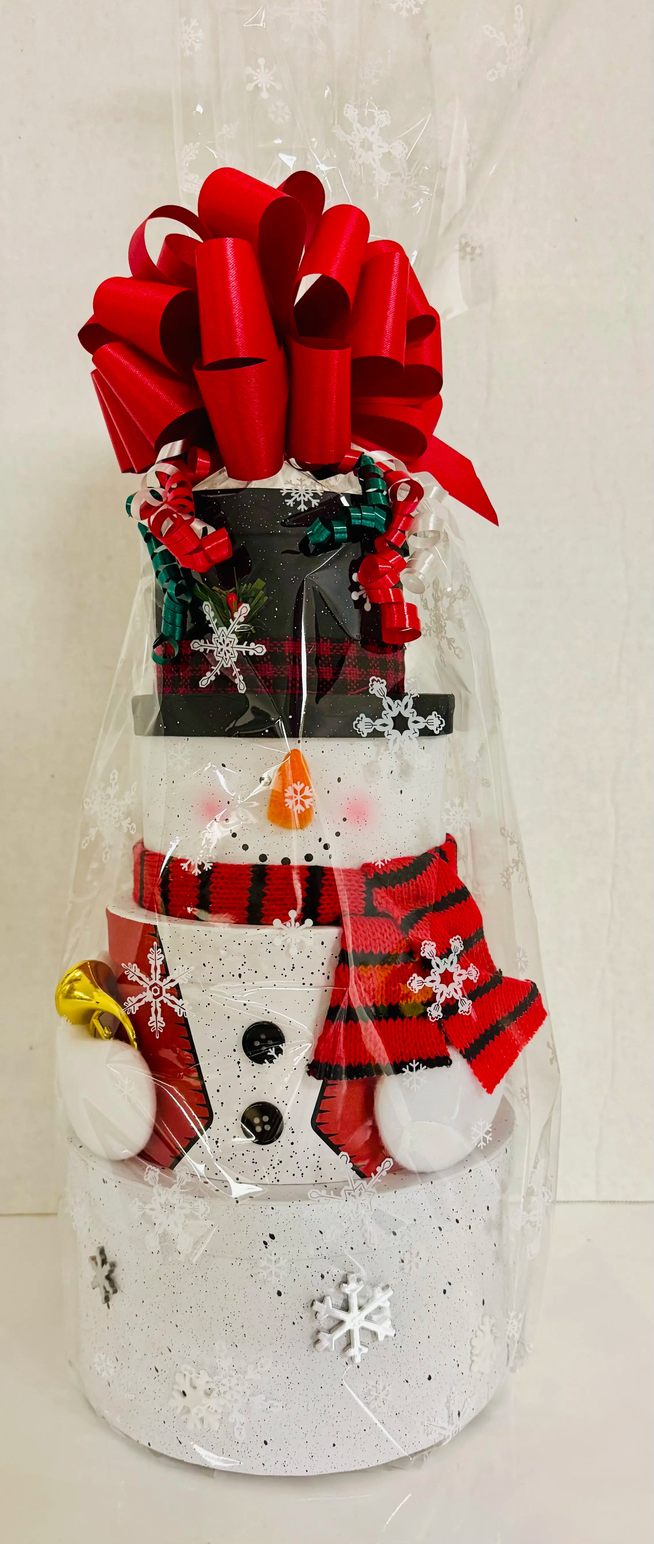 Decorative snowman-shaped container with a black top hat, red scarf, and striped socks on a white background.