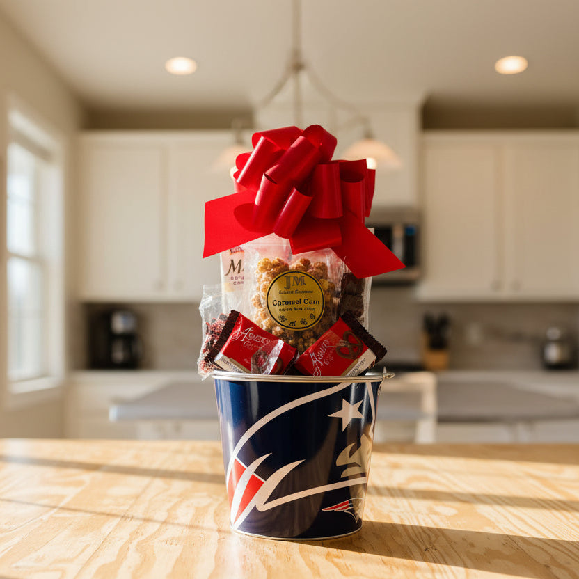 Gift basket with snacks and a red bow in a metal container with a logo on a wooden floor.