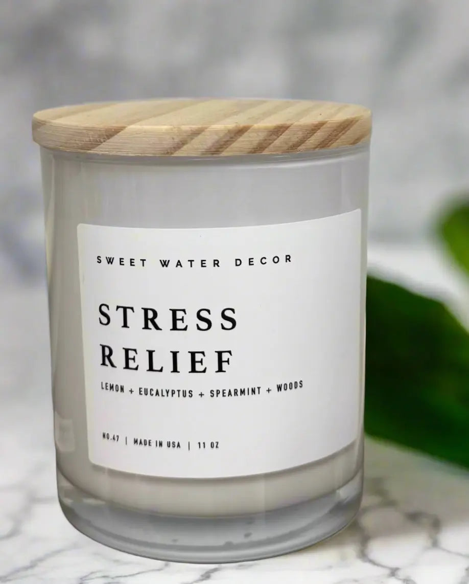 Candle labeled 'Stress Relief' by Sweet Water Decor on a marble surface with a blurred background