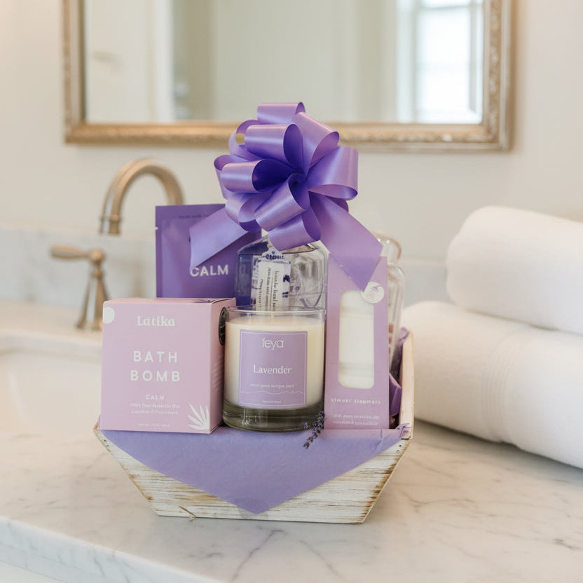 Gift basket with lavender candle, bath bomb, and other items on a wooden surface.