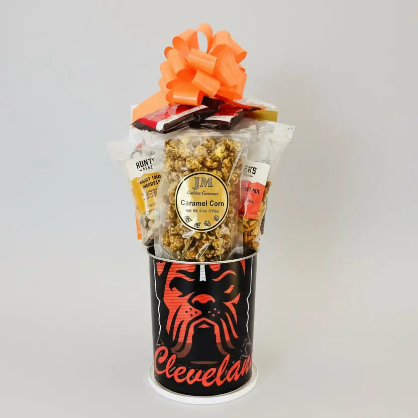 Gift basket with popcorn and candy in a Cleveland-themed container on a wooden surface.