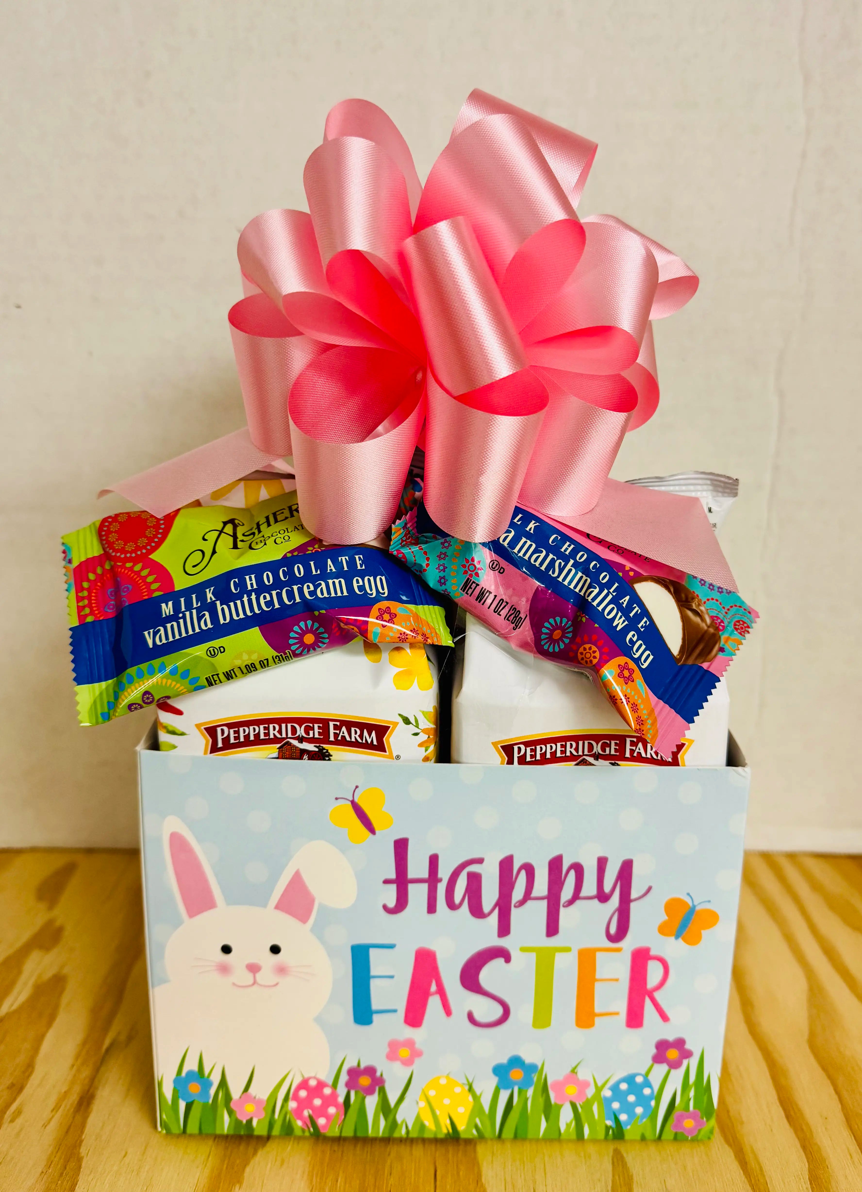 Easter gift basket with candy and a pink bow on a wooden surface.