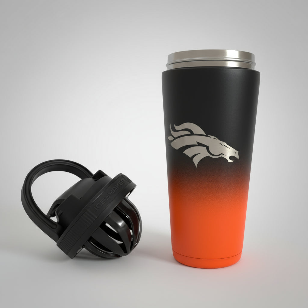 Black and orange tumbler with a logo on a wooden surface with greenery