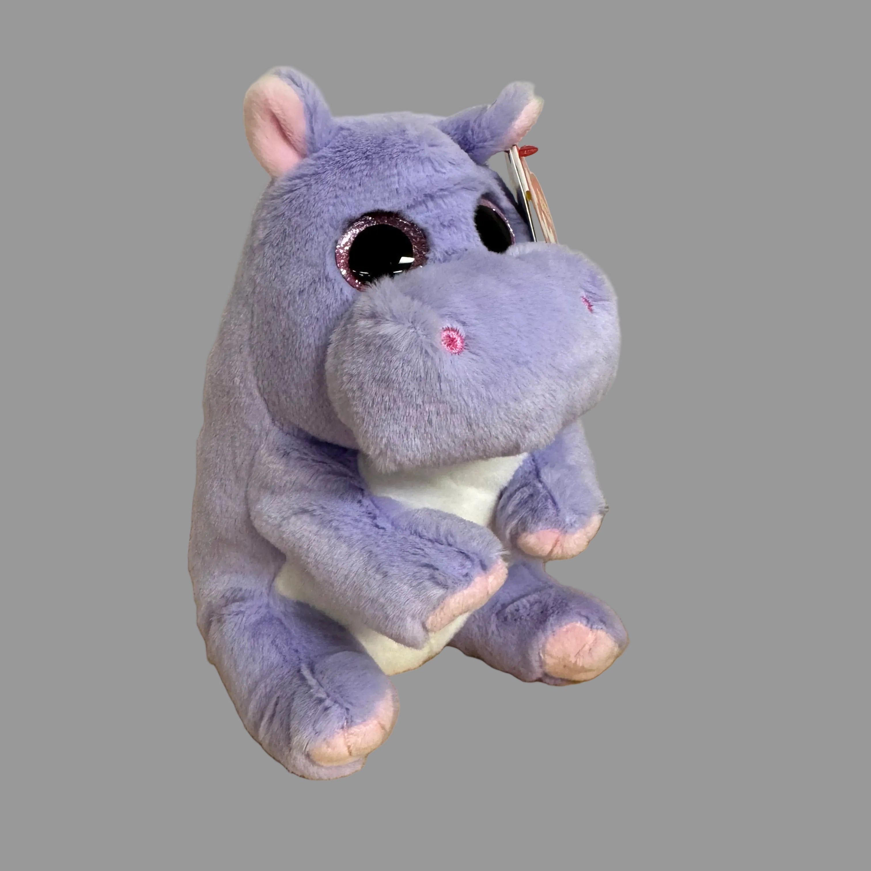 Purple hippo plush toy on a wooden floor against a beige wall