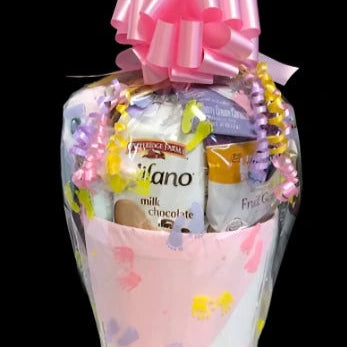 Gift basket with a pink bow and colorful packaging on a black background