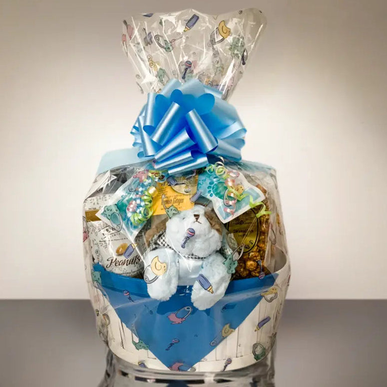 Gift basket with snacks, a teddy bear, and a blue bow on a white background