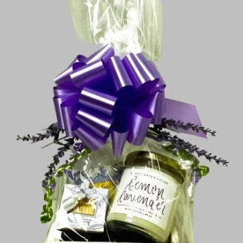 Gift basket with a purple bow, lemon lavender product, and other items on a gray background