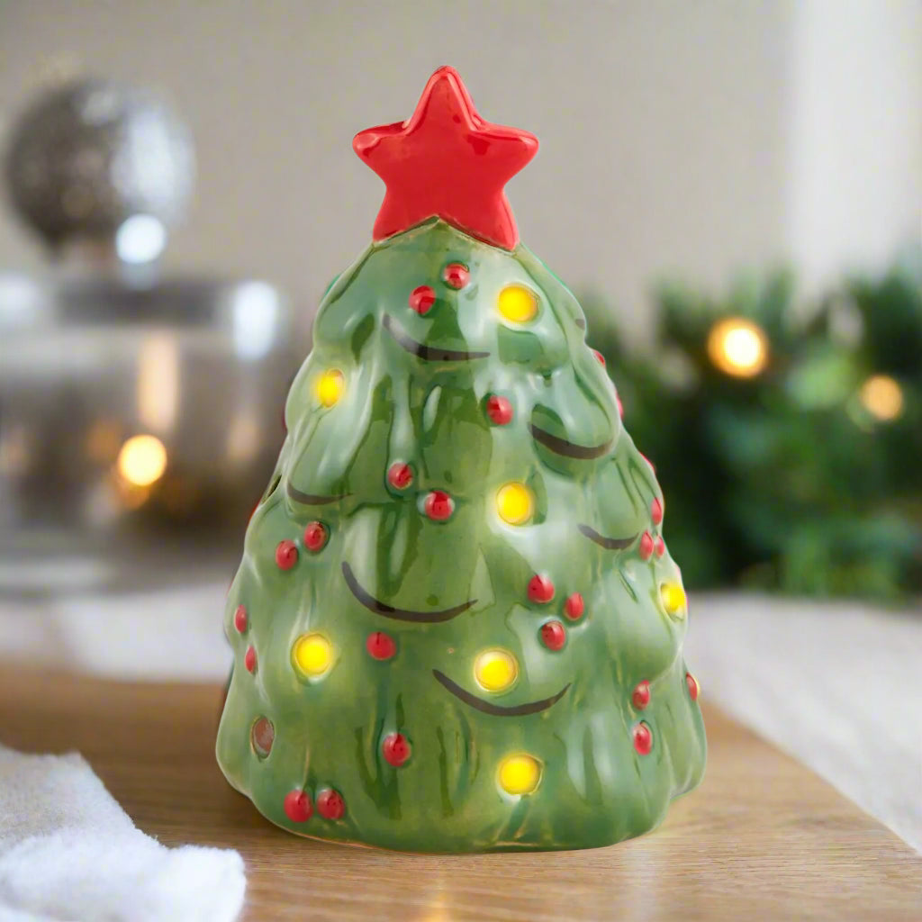 Decorative Christmas tree-shaped candle with a red star on top against a white background