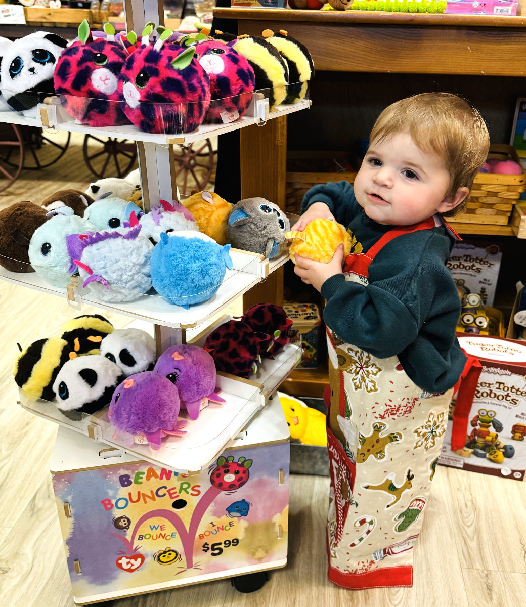 Child holding a toy in front of a display of Bean Bouncers toys in a store.