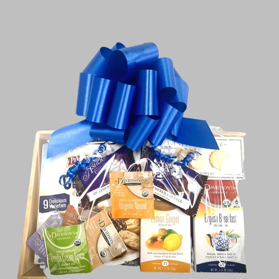 Gift basket with a blue bow containing various food items on a gray background