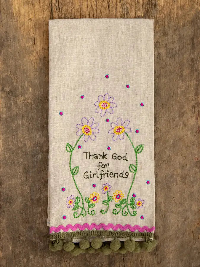 Embroidered towel with floral design and text on a wooden background