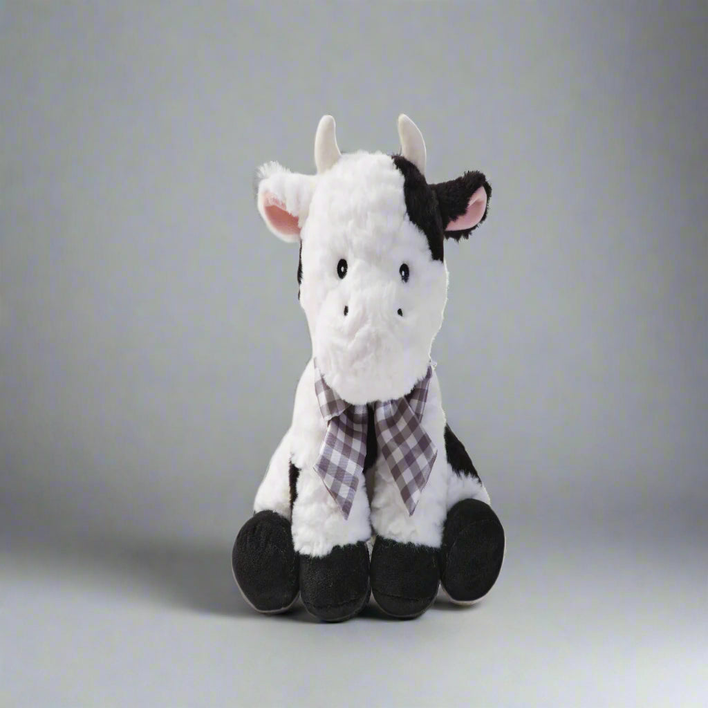 Plush cow toy with a checkered scarf on a white background
