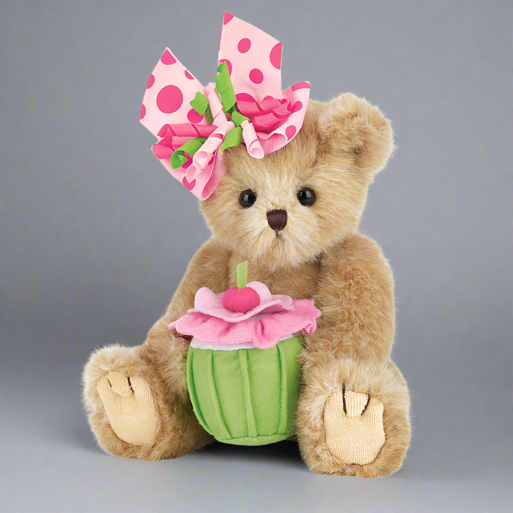 Teddy bear with a pink flower and green cupcake toy on a gray background