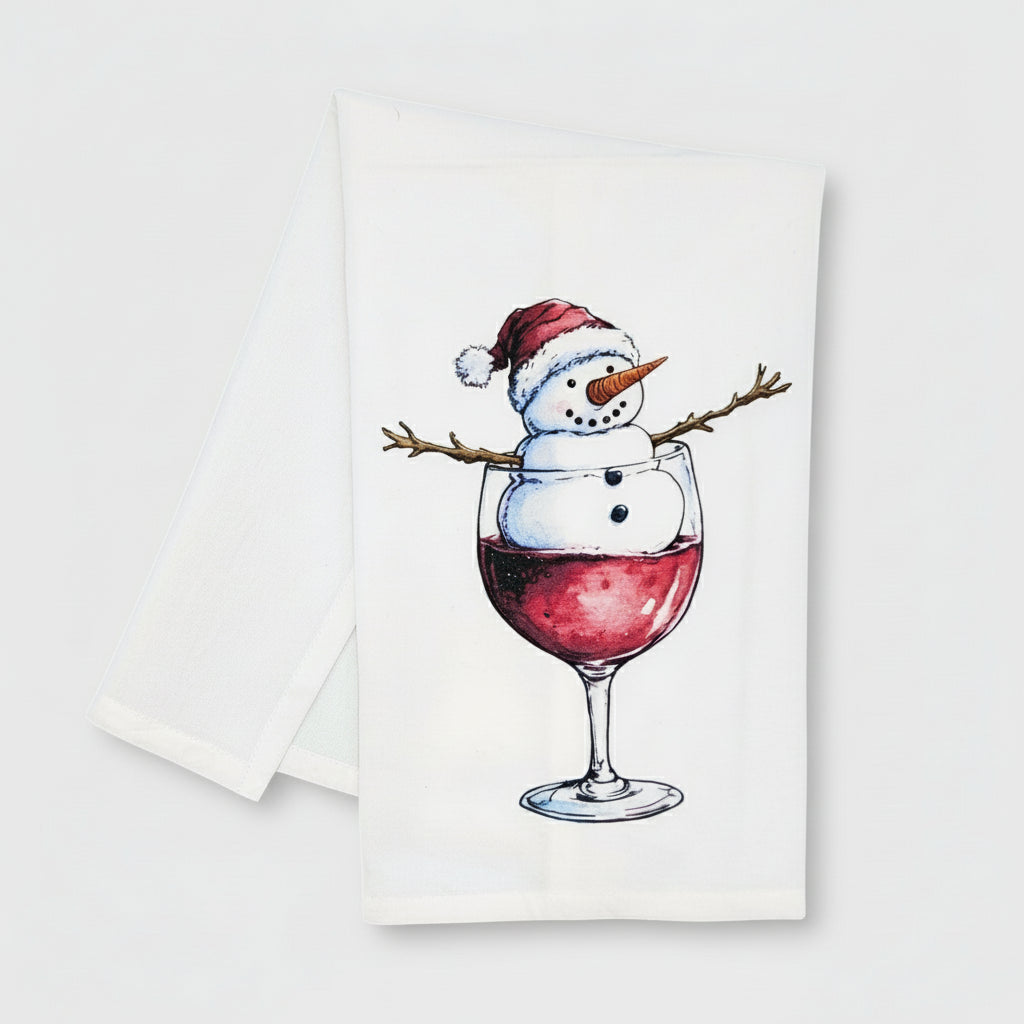 Towel with a snowman design inside a wine glass filled with red wine on a white background