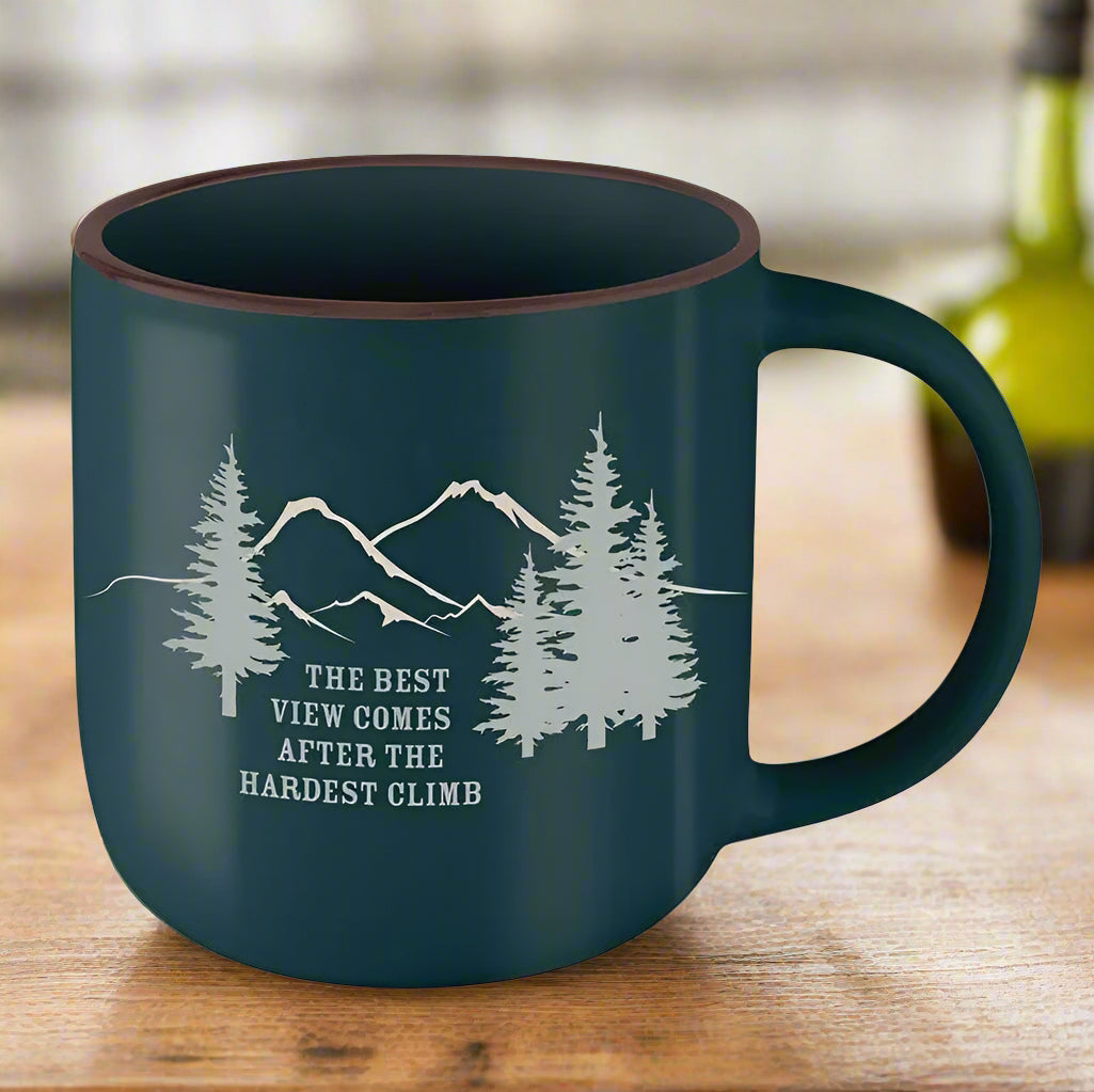 Green mug with mountain and tree design and motivational quote on a kitchen