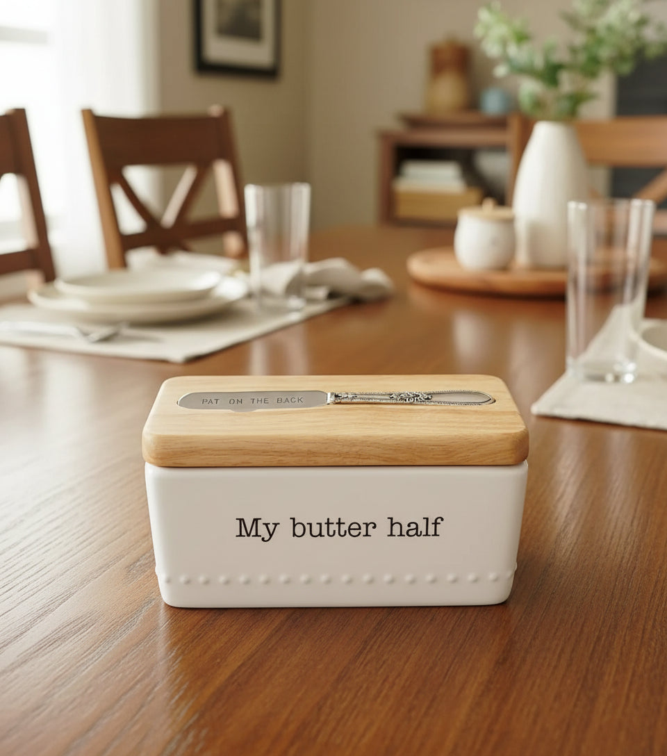 Butter dish with wooden cover and silver knife on a white background