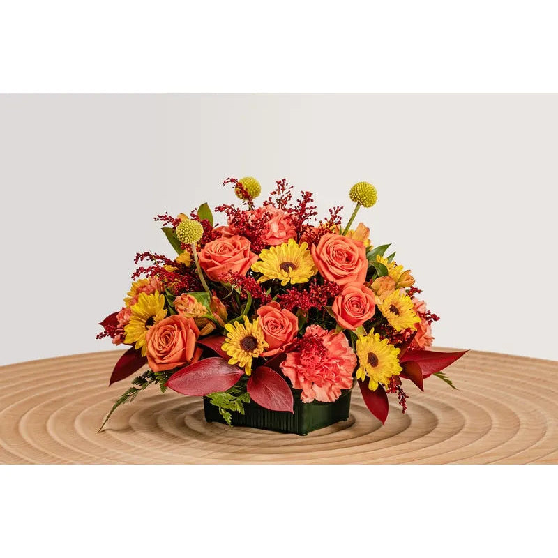 Colorful flower arrangement on a wooden surface with a light gray background