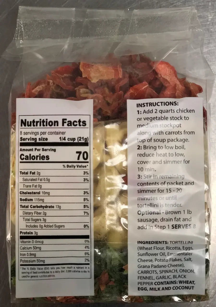 Bowl of pasta with carrots and chicken on a decorative plate with a spoon beside it.