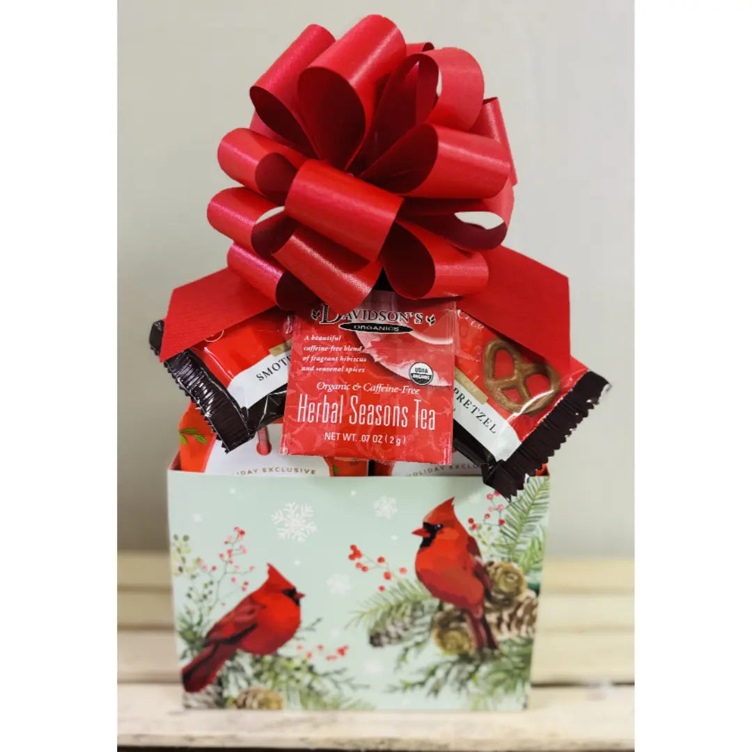 Gift basket with a red bow, tea packages, and a card featuring cardinals on a white background.