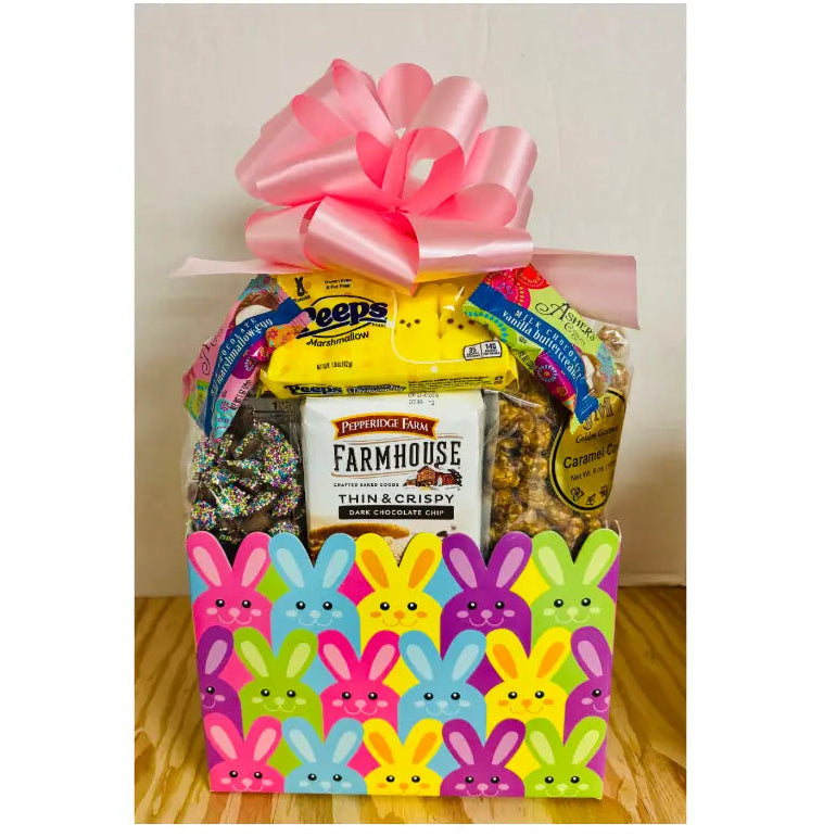 Gift basket with a pink bow, Peeps packaging, and a box of Farmhouse brand cookies on a wooden surface.