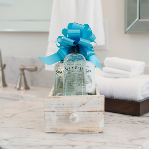 Gift set with bottles in a wooden box and blue bow on a white background
